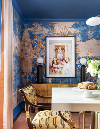 A dining room with blue walls and gold leaf wallpaper.