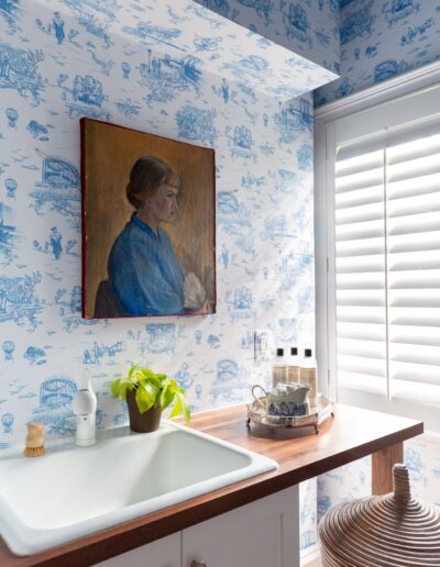 A bathroom with blue toile wallpaper and a sink.