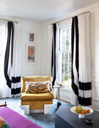 A living room with two windows and a yellow chair