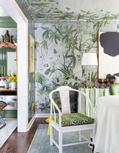 A room with a green and white wall, a table, chairs, and a mirror.