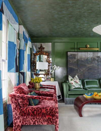 A living room with green walls and blue patterned curtains.