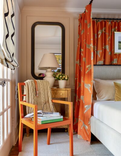 A bedroom with orange curtains and a mirror