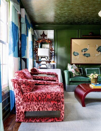 A living room with green walls and red chairs.