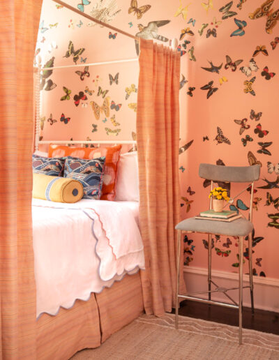 A bedroom with pink walls and butterfly wallpaper.