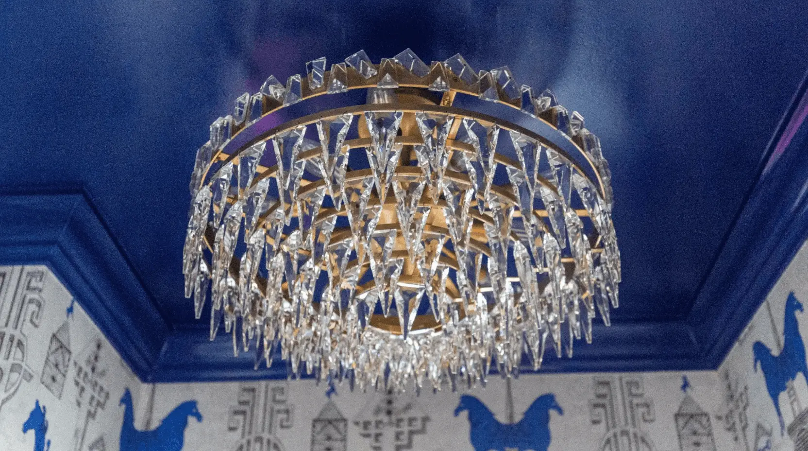 Circular crystal chandelier against deep blue ceiling